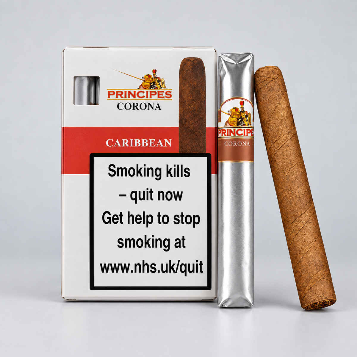 Principes Corona Caribbean cigar packaging and two cigars on a light gray studio background. The box shows the Principes Corona branding and a large smoking-health warning label.