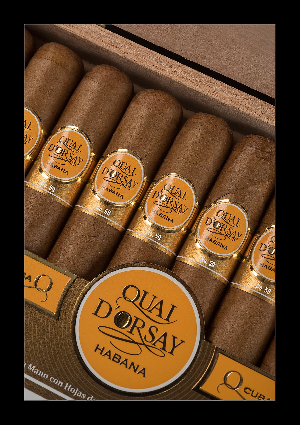 A close-up of several brown cigars arranged in a wooden box, each with a gold band labeled 'QUAL D'ORSAY HABANA'.
