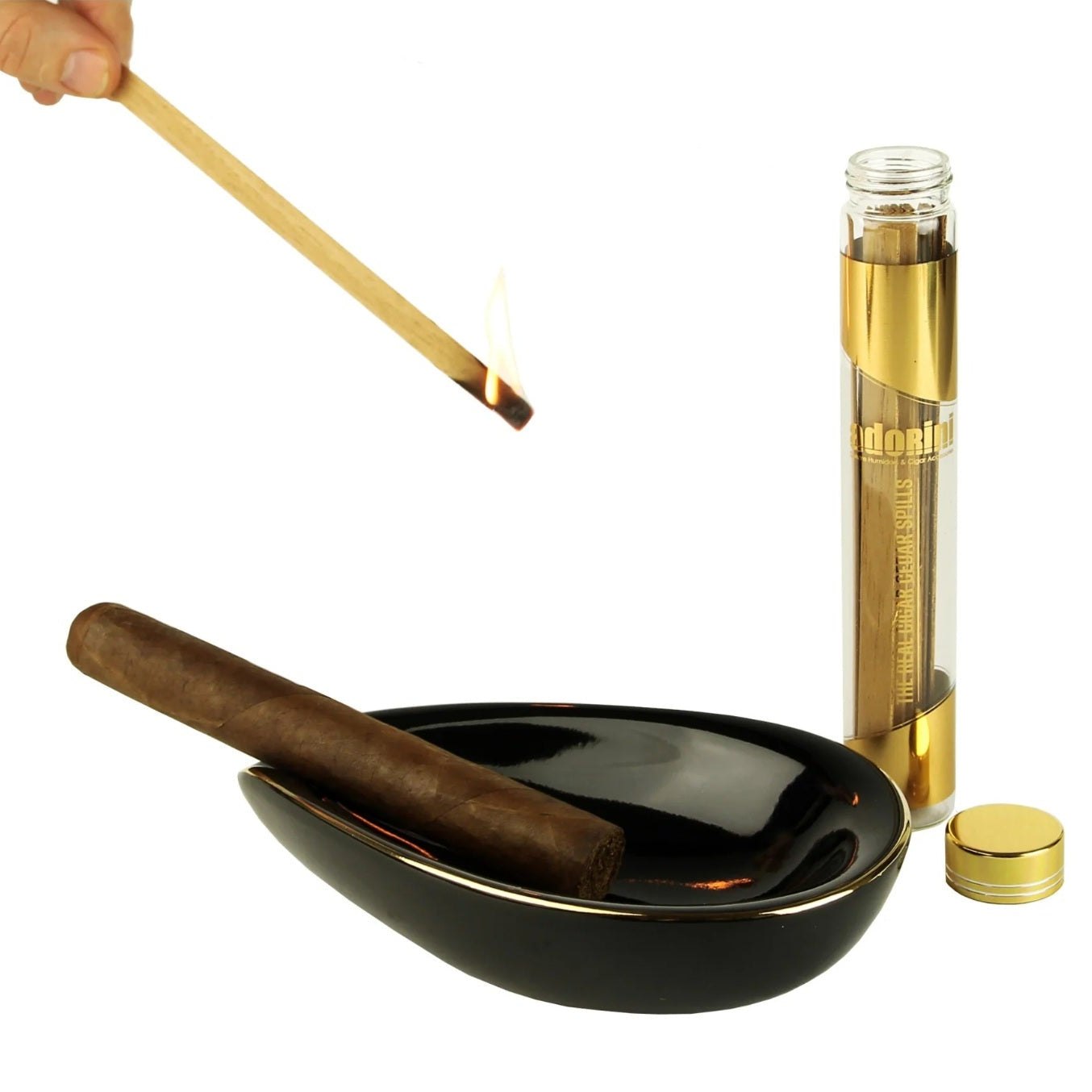 Cigar with a black ashtray, wooden lighter, and a gold-topped glass container on a white background.
