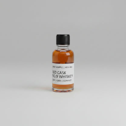 Small bottle of RED CASK NO.9 whiskey with a label on a light pink background