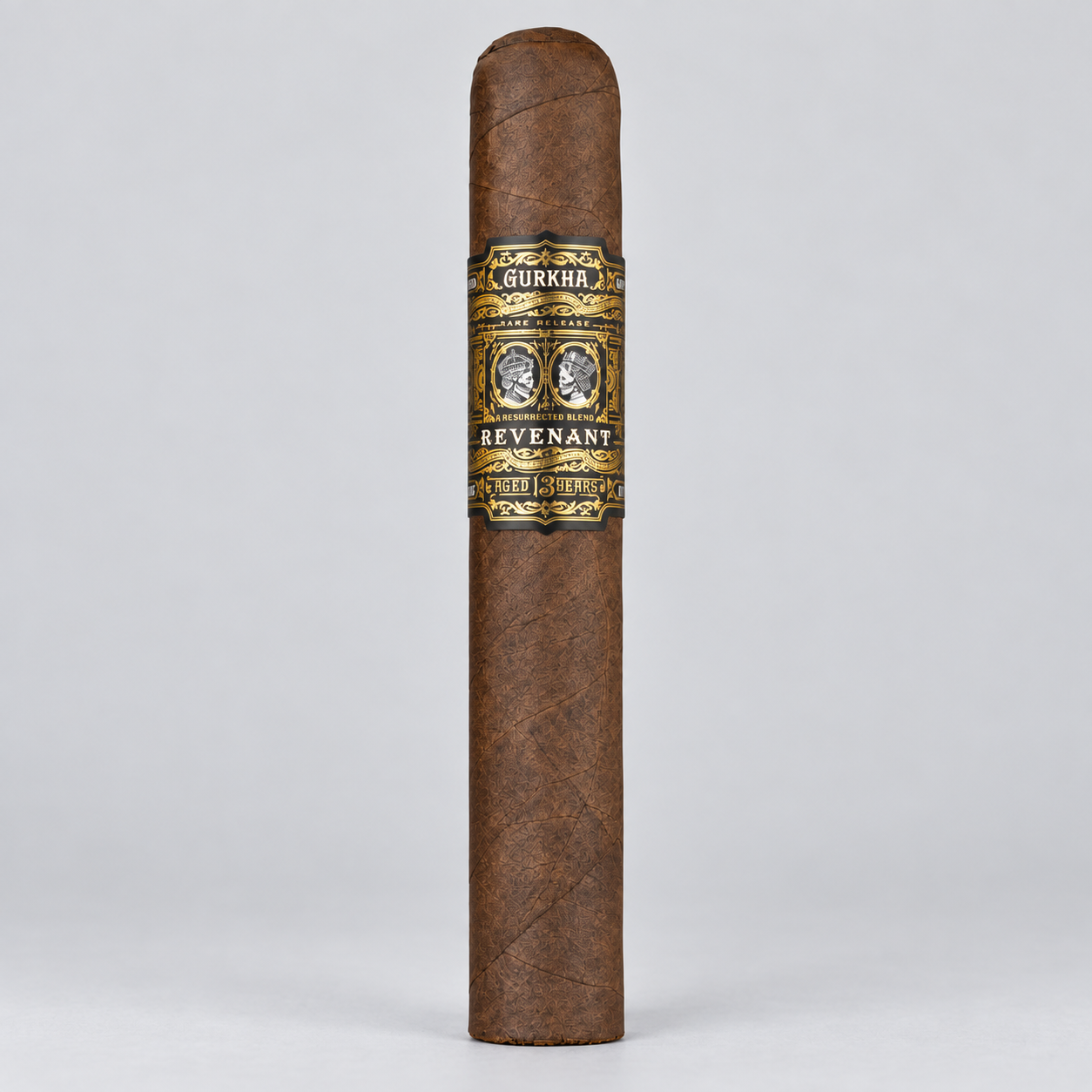 A single brown cigar standing upright on a light gray background, featuring a decorative band with the brand name Gurkha and the variant name Revenant.