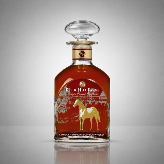A bottle of Rock Hill Farms Single Barrel Bourbon Whiskey with a clear glass stopper, featuring a red label with a gold horse illustration, set against a neutral gray background.