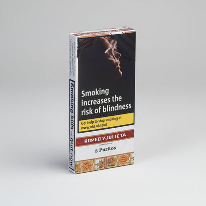 A 5-pack box of Romeo y Julieta Persimona Cura 5 Puritos cigarillos, featuring a prominent smoking warning label on the front with an image of a person smoking and text about blindness.