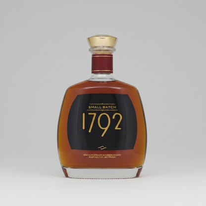 A bottle of 1792 Small Batch Kentucky Straight Bourbon Whiskey with amber liquid, a black label with gold lettering, and a gold cap, isolated on a white background.