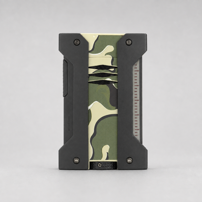 A rectangular ST DUPONT LIGHRTER with a black rugged frame and a central camouflage pattern panel in green, beige, and black, shown against a neutral gray background.