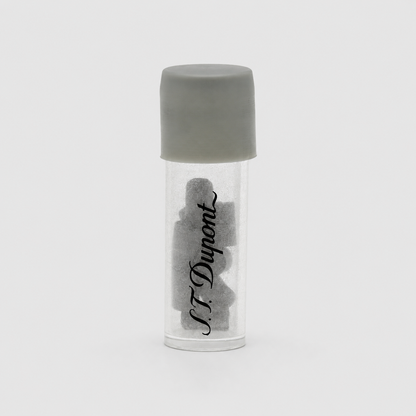 A small clear cylindrical vial with a gray screw cap, containing several dark gray irregular pieces, with the brand name 'N.F.