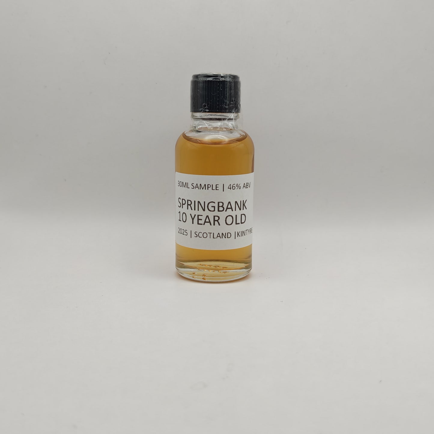 Small bottle of Springbank 10 Year Old whisky sample on a gray background