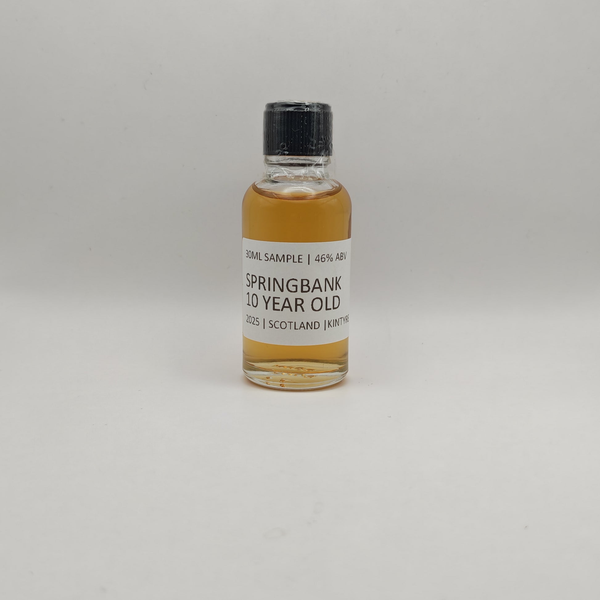 Small bottle of Springbank 10 Year Old whisky sample on a gray background