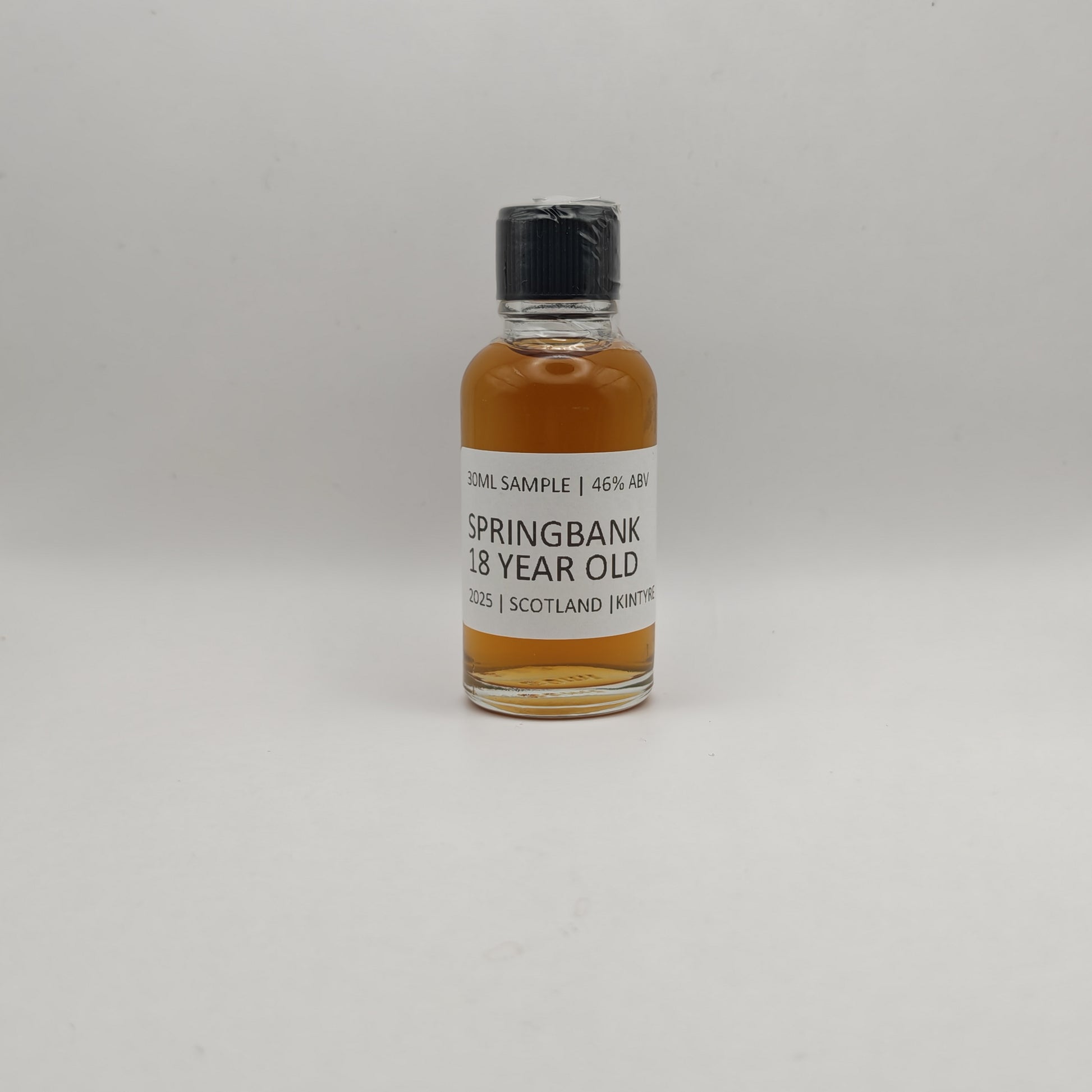 Small bottle of Springbank 18 year old whisky sample on a gray background