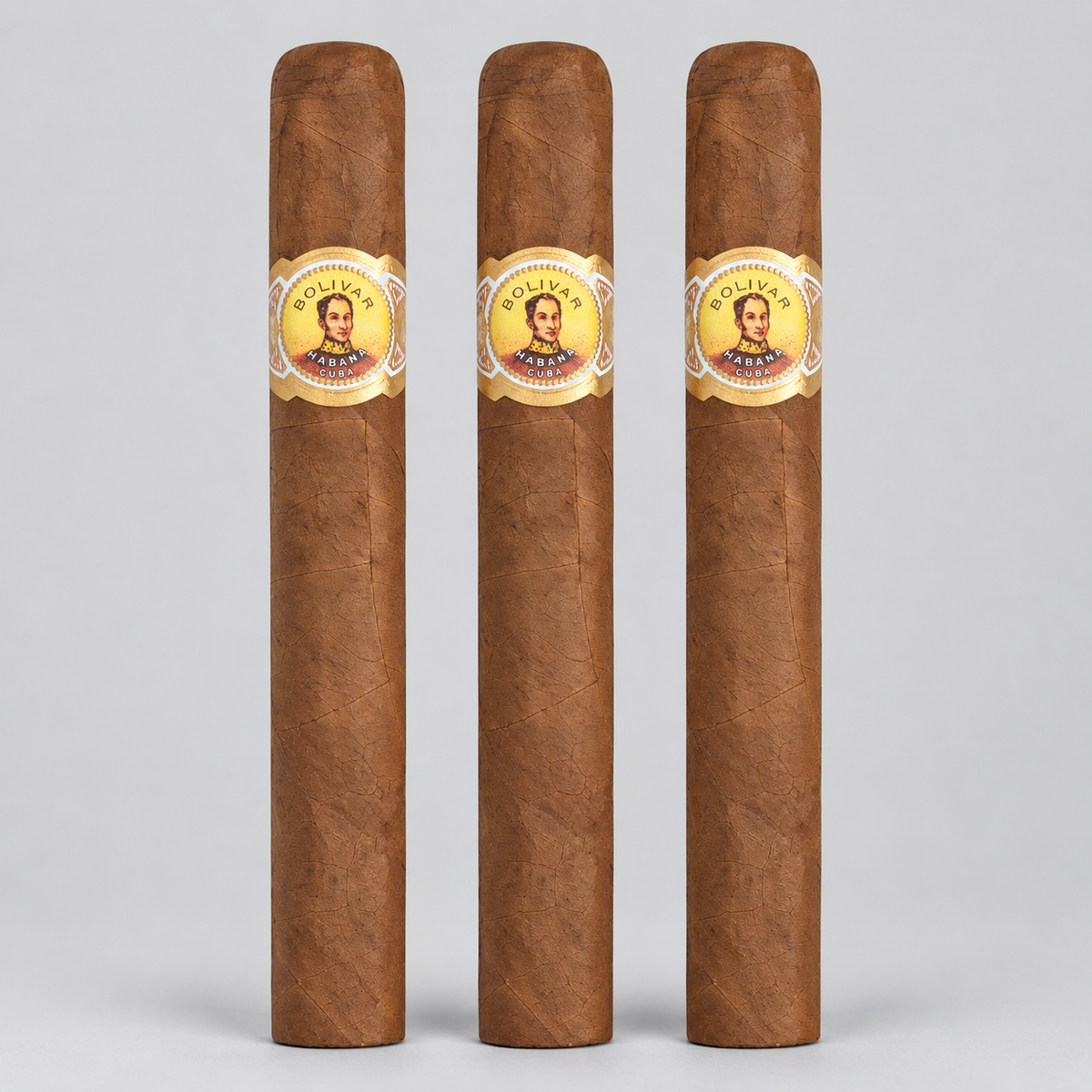 Three brown cigars standing upright side by side on a light gray background, each with a circular gold and white band featuring a portrait and the text 'Cigars El Granado'.