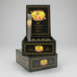 A stack of black and gold Mavila Robusto cigar boxes, with the top box open to display a single rolled cigar and several cigars inside, set against a neutral gray background.