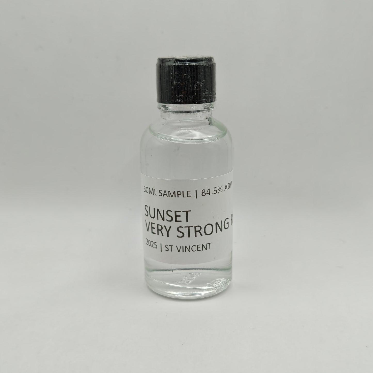 Small glass bottle of Sunset Very Strong Rum with a black cap on a gray background