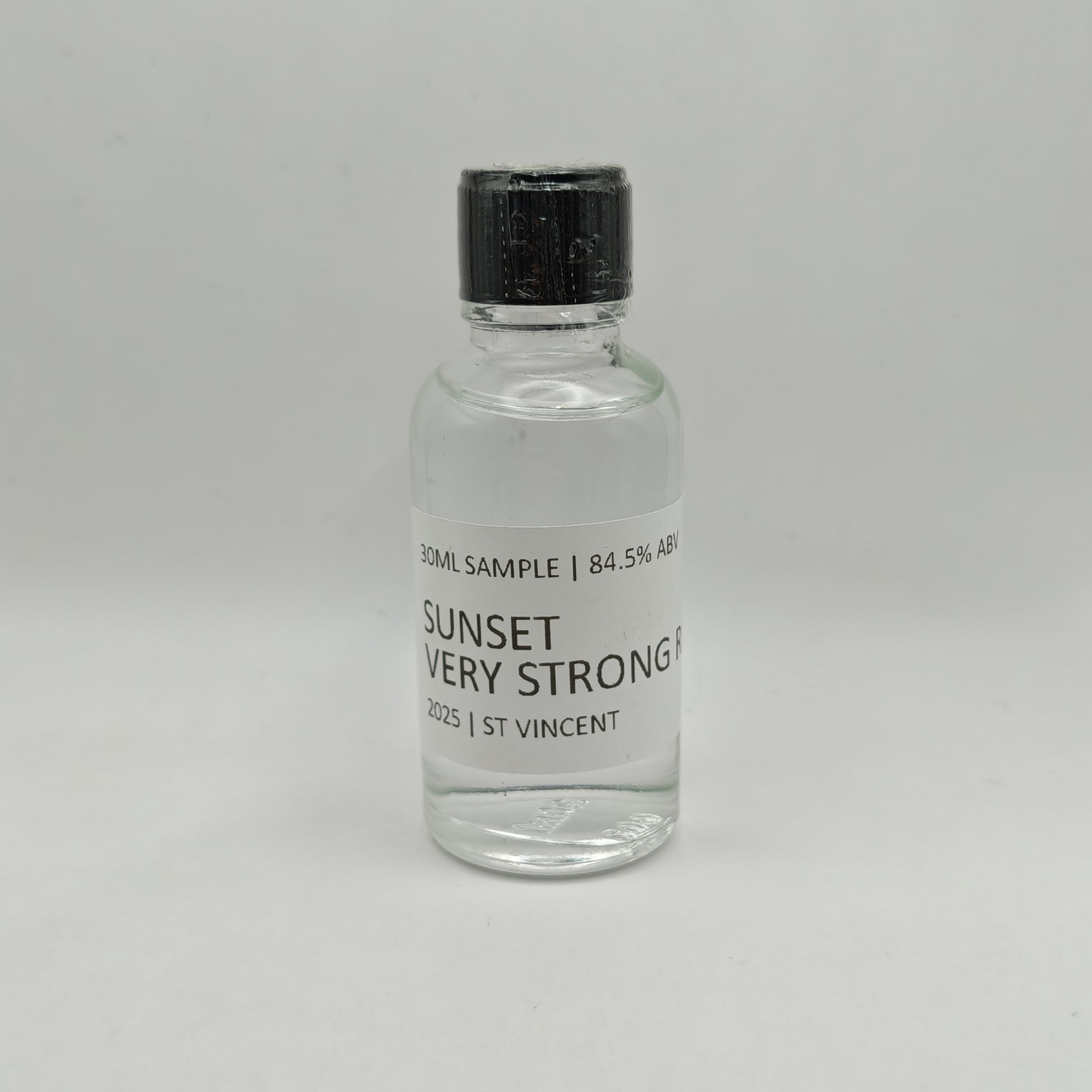 Small glass bottle of Sunset Very Strong Rum with a black cap on a gray background