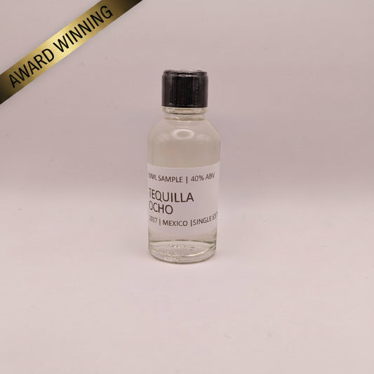Tequila Ocho bottle with a black cap on a light pink background
