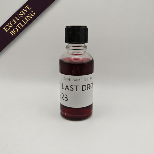 Small bottle with red liquid and a black cap on a white background, featuring 'The Last Drop' branding.