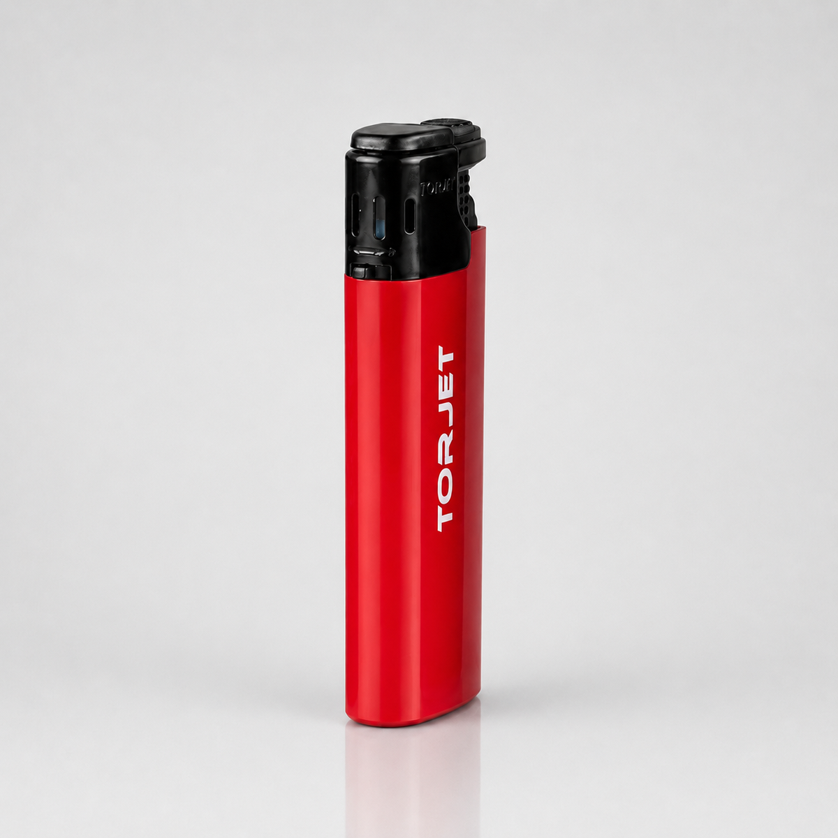 A TorJet portable torch lighter with a metallic red body and a black top ignition cap, standing upright on a light gray reflective surface.