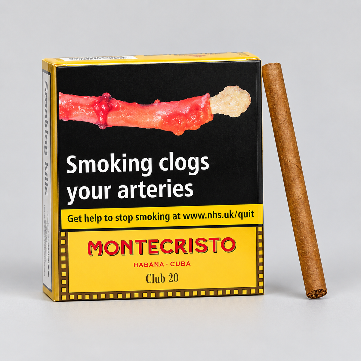 A Montecristo Club 20 Havana cigar shown standing upright next to its retail packaging box on a light gray background. The box features a prominent health warning graphic.