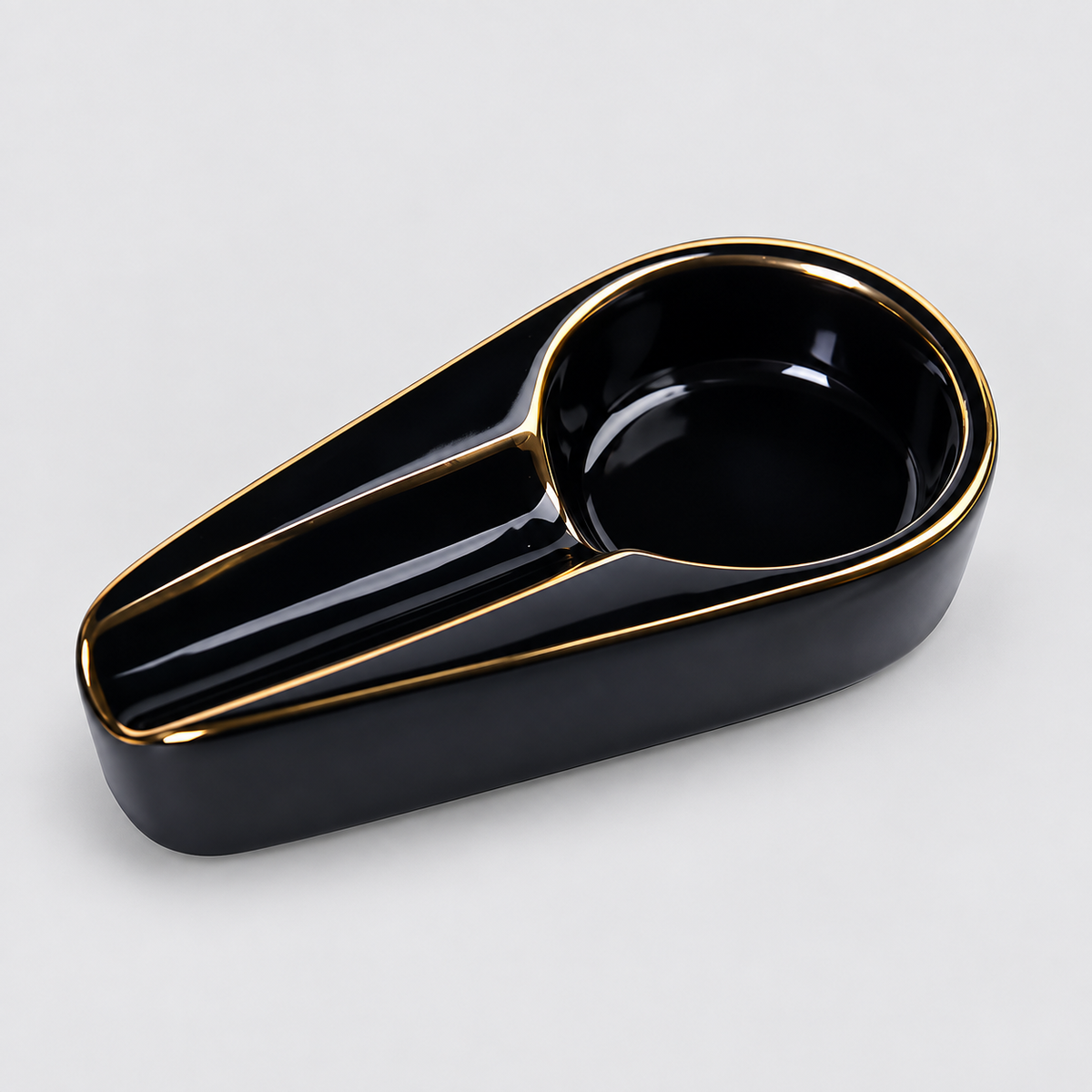 A glossy black ceramic ashtray with a gold-trimmed rim and gold dividing lines, shown on a light gray background.