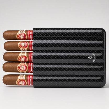 A black carbon-fiber-pattern cigar humidor holding five cigars with red and gold bands, photographed on a light gray studio background.