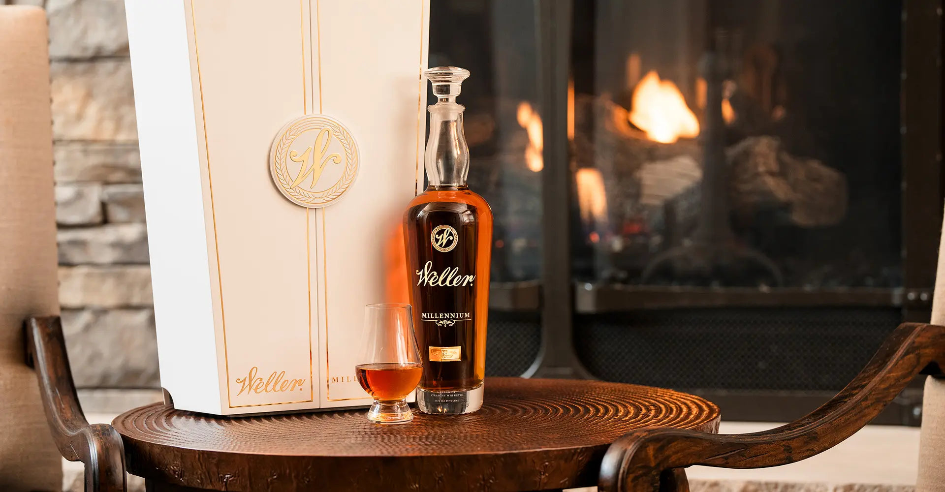 Bottle of Weller Millennium whiskey on a wooden table with a fireplace in the background