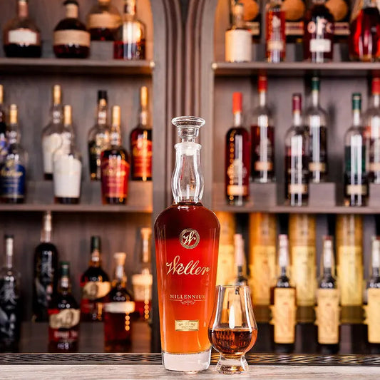 Weller whiskey bottle with a glass on a bar shelf with various bottles in the background