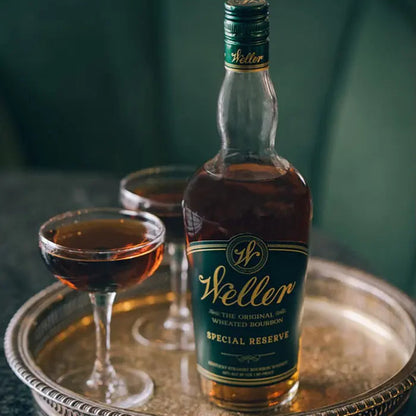 A bottle of Weller Special Reserve bourbon on a tray with two glasses of the drink.