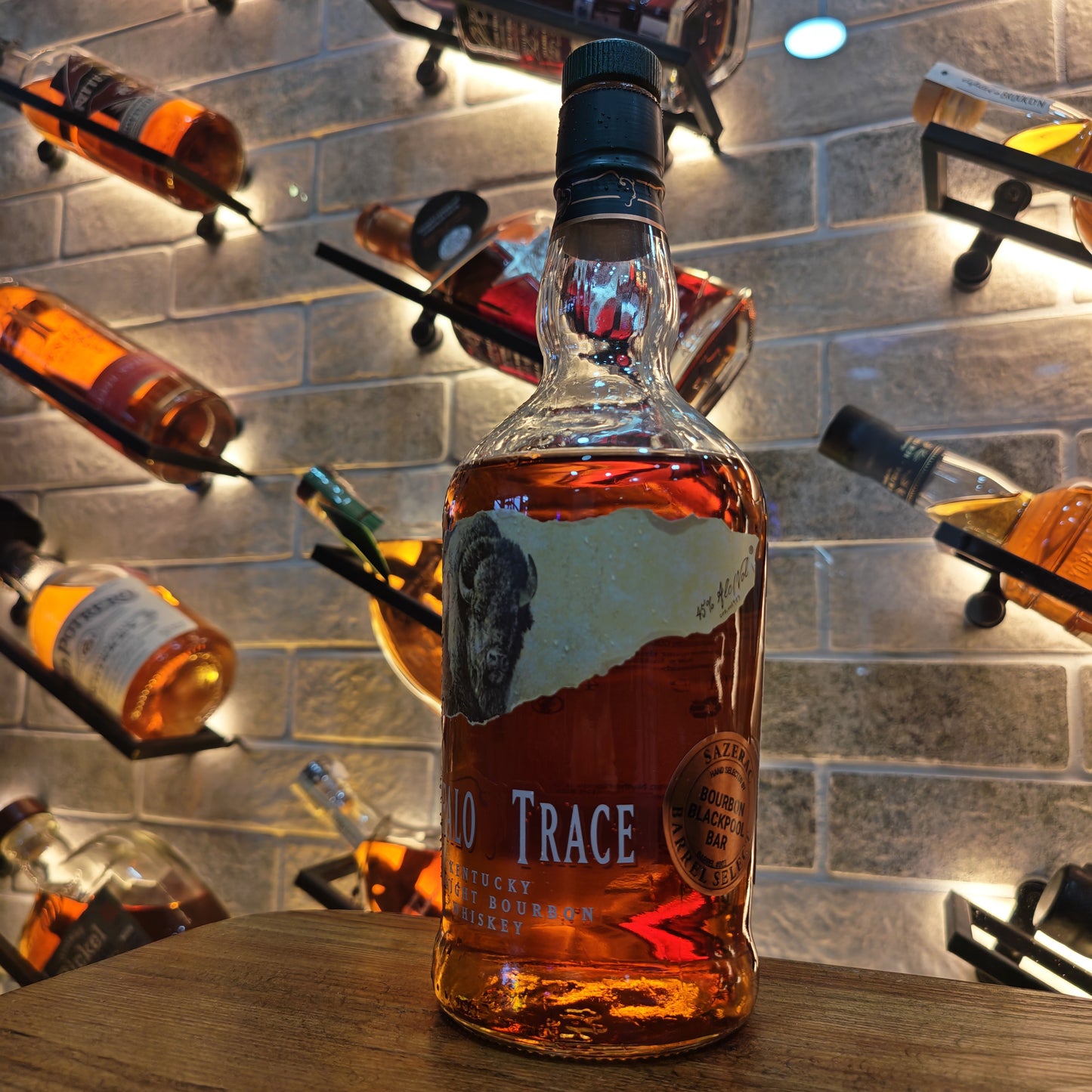 Bottle of 'Buffalo Trace' bourbon on a bar with other bottles in the background.