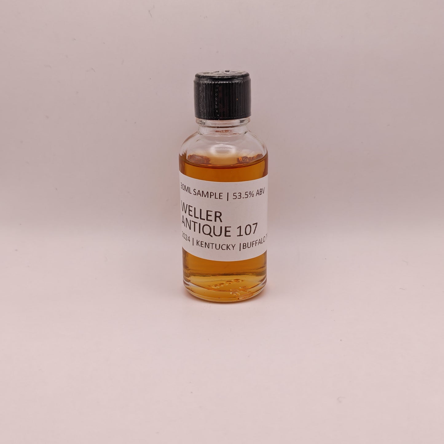 Small bottle of Weller Antique 107 whiskey sample on a light gray background