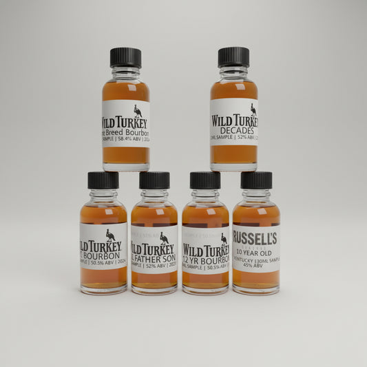 Collection of Wild Turkey bourbon bottles on a bar counter with a blurred bar background.