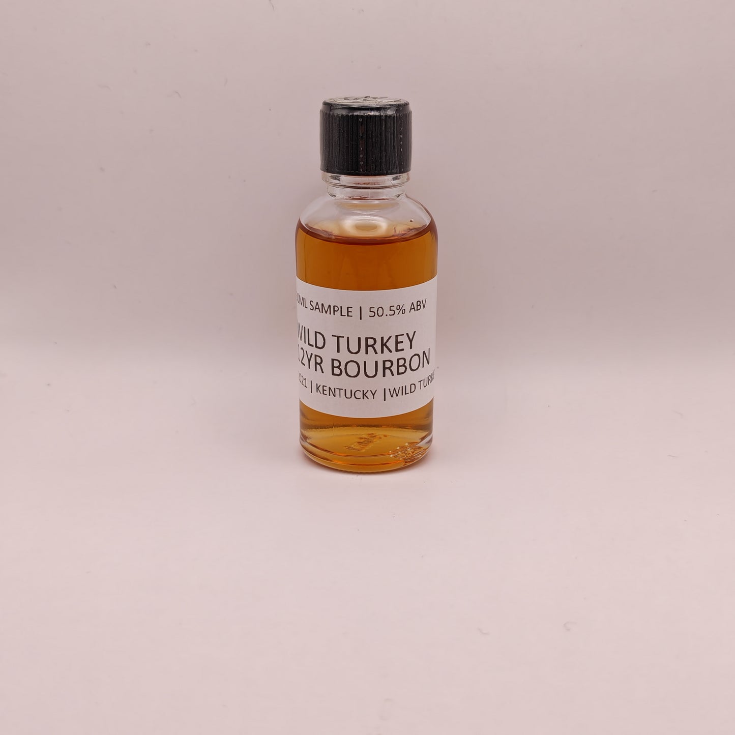 Small bottle of Wild Turkey bourbon on a light gray background