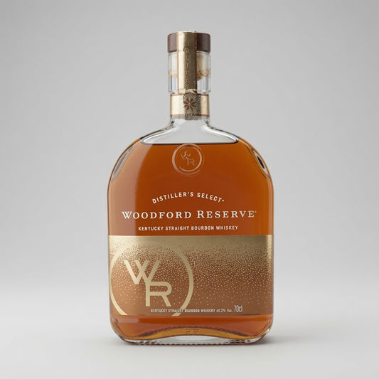 A bottle of Woodford Reserve Kentucky Straight Bourbon Whiskey on a neutral gray background. The clear glass bottle showcases the amber-brown whiskey inside, featuring a metallic gold and white label with the brand's 'WR' logo and a gold neck seal.