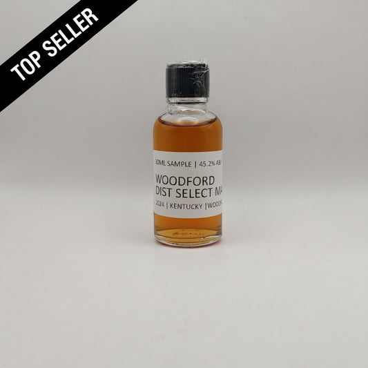 Small bottle of Woodford Reserve whiskey sample on a gray background