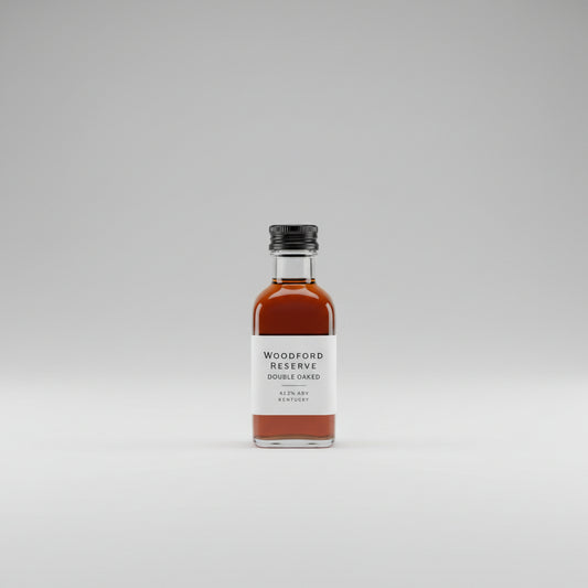 Bottle of Woodford Reserve Double Oaked bourbon on a reflective surface with a bar setting in the background.