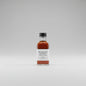 Bottle of Woodford Reserve Double Oaked bourbon on a reflective surface with a bar setting in the background.