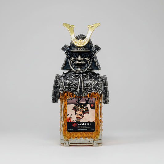 A bottle of Yamato Sakai whisky featuring a detailed black and silver samurai helmet and mask bottle cap, with amber-colored whisky visible inside a textured glass bottle and a Japanese label on the front.