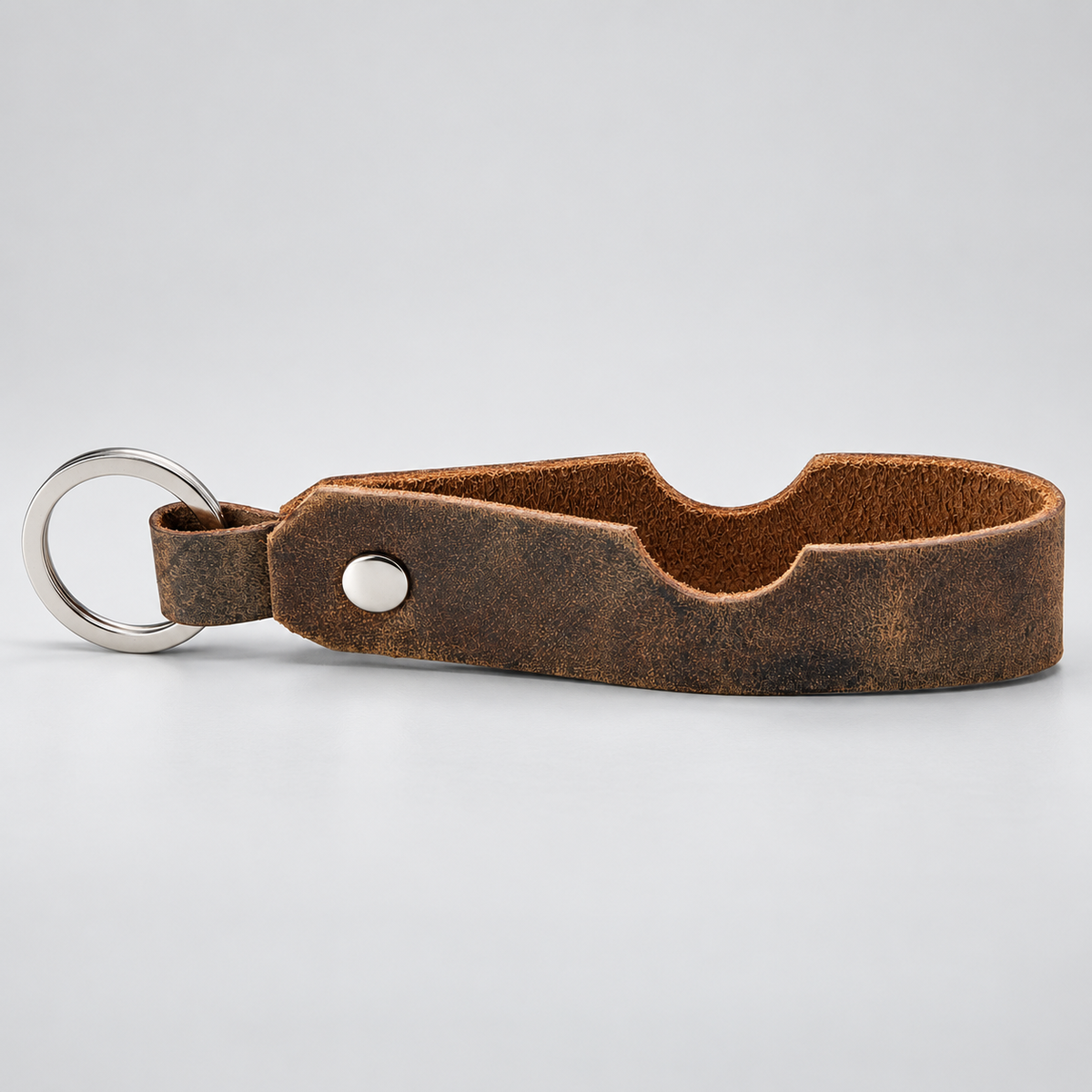 A brown distressed leather bottle opener keychain with a silver metal split ring and a silver rivet, shown on a light gray background.