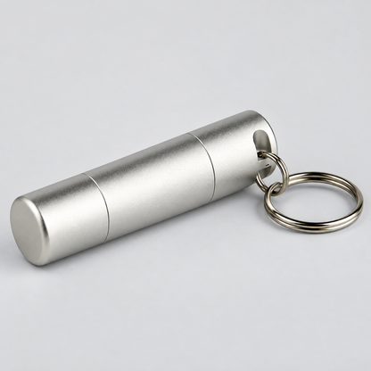 A silver aluminum cylindrical keychain container with a matching metal key ring, shown on a light gray background.