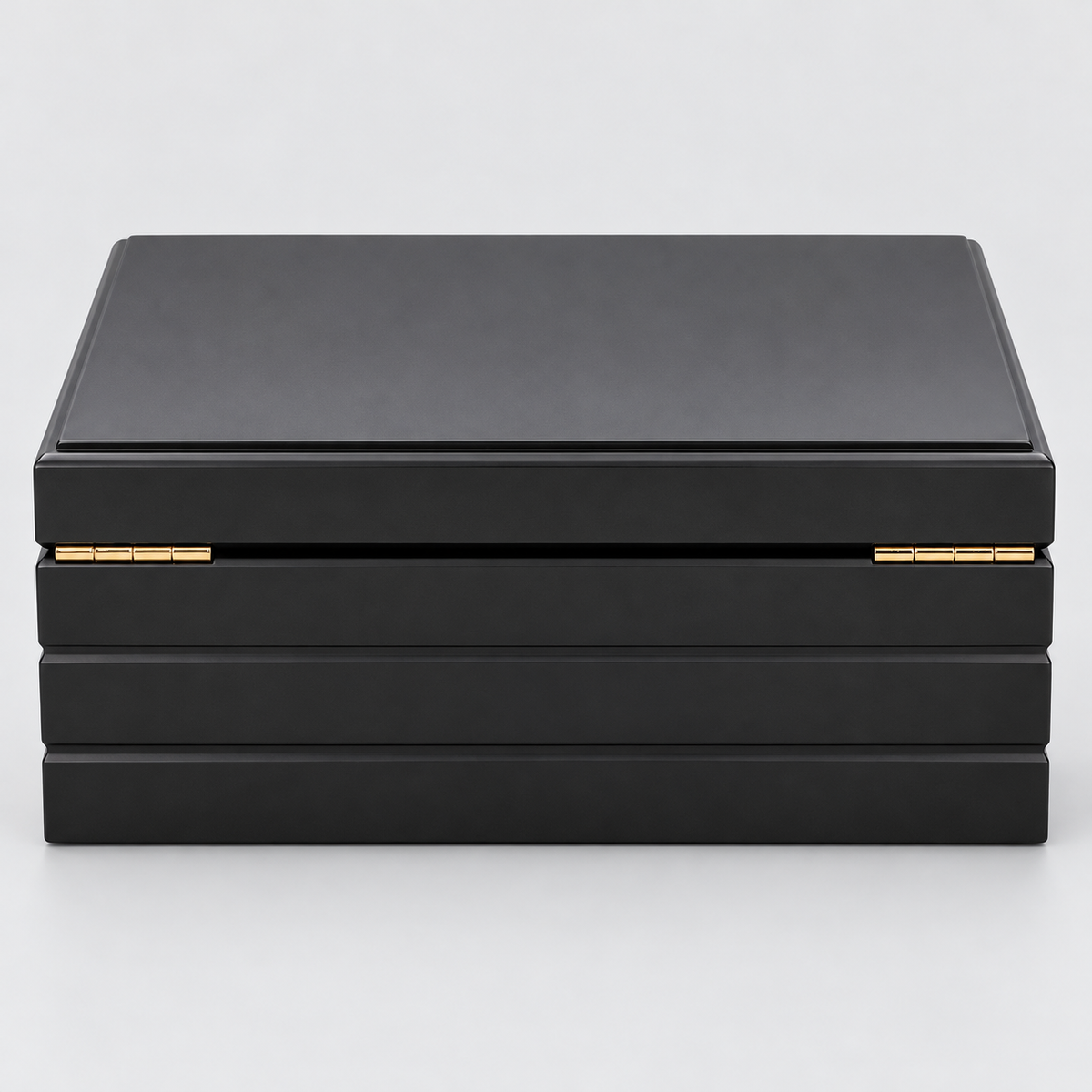A black rectangular HUMIDOR box with a hinged lid and small gold-tone metal accents on the front, photographed on a clean light gray background.