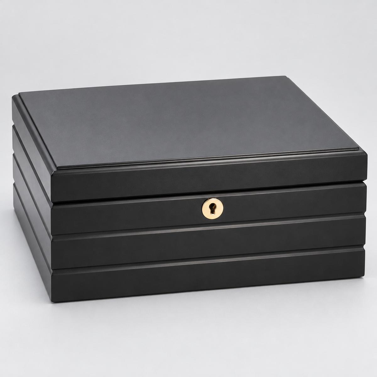 A black rectangular HUMIDOR box with a hinged lid, featuring a small round gold-tone keyhole detail on the front and a lock, set against a light gray background.