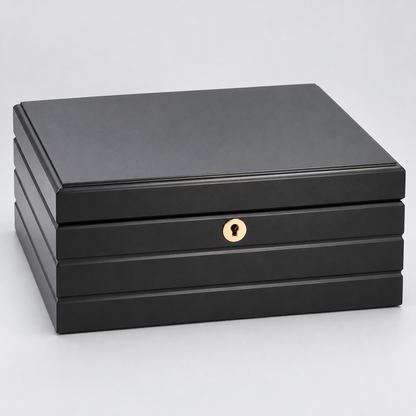 A black rectangular HUMIDOR box with a hinged lid, featuring a small round gold-tone keyhole detail on the front and a lock, set against a light gray background.