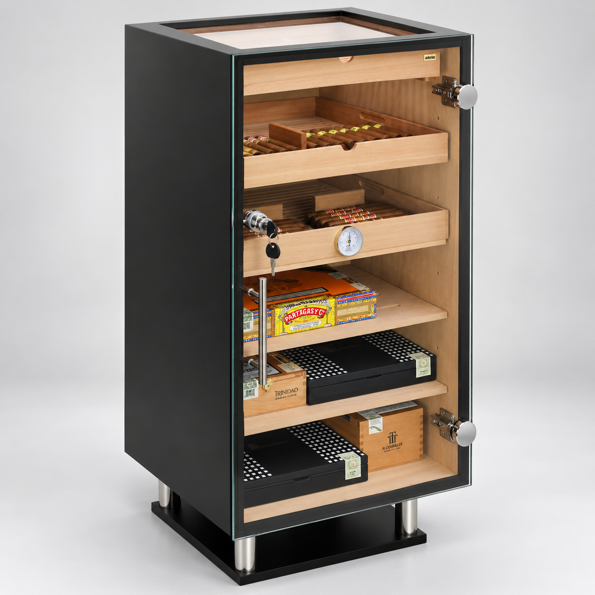 A black humidor cabinet with its door open, showing wooden interior shelves holding cigars, trays, and a hygrometer. The cabinet stands on metal legs against a light gray studio background.