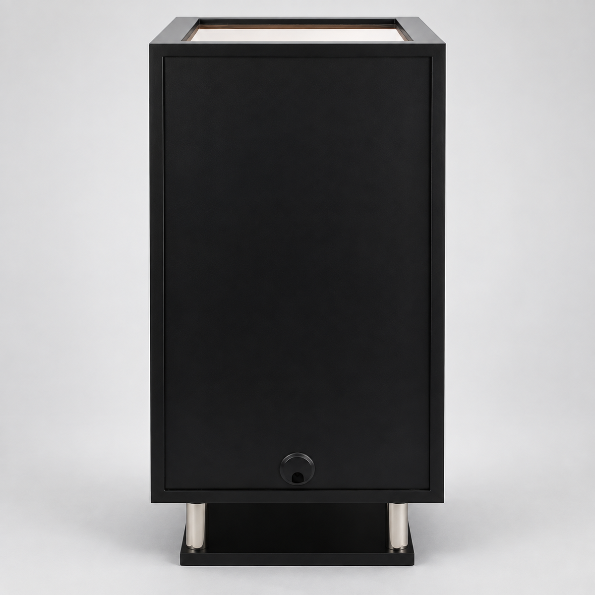 A modern black rectangular outdoor speaker or speaker enclosure with a top-facing light or opening, supported by two silver cylindrical legs on a light gray background.