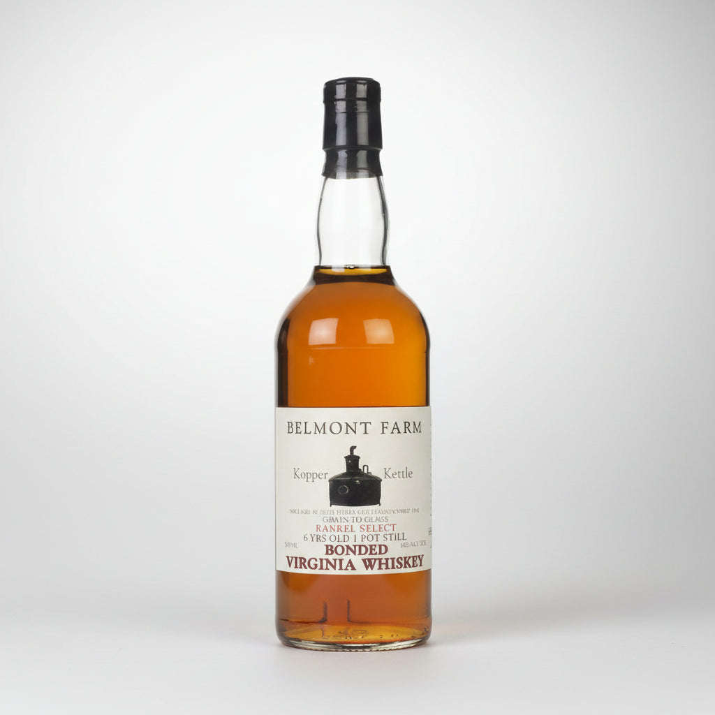 A bottle of Belmont Farm Kopper Kettle Virginia Whiskey, showing the amber liquid inside a clear glass bottle with a black cap and a white label.