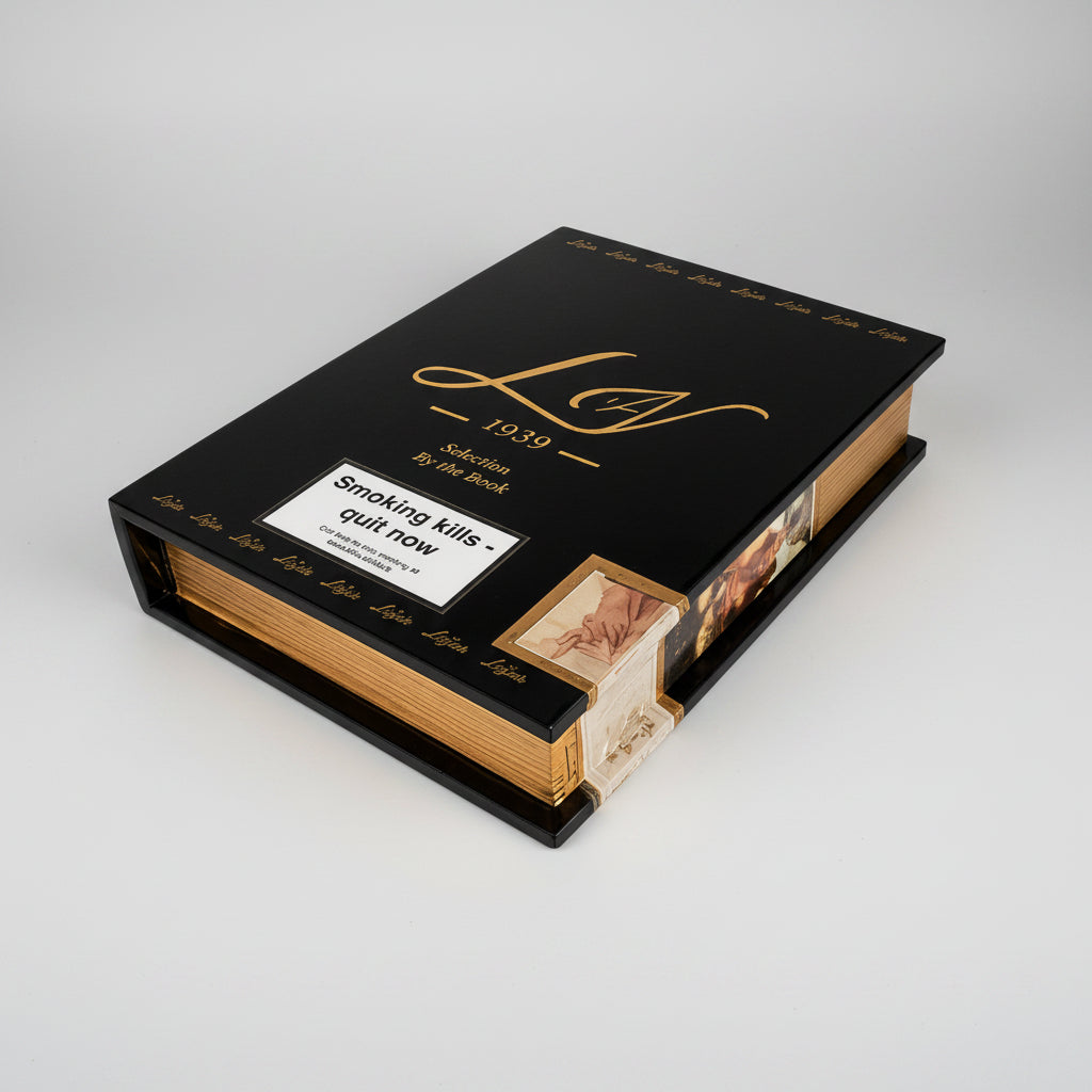 A hardcover book-shaped cigar case with a black cover, gold lettering, and a white rectangular sticker on the front. The sticker reads 'Smoking kills quit now' with smaller text below.