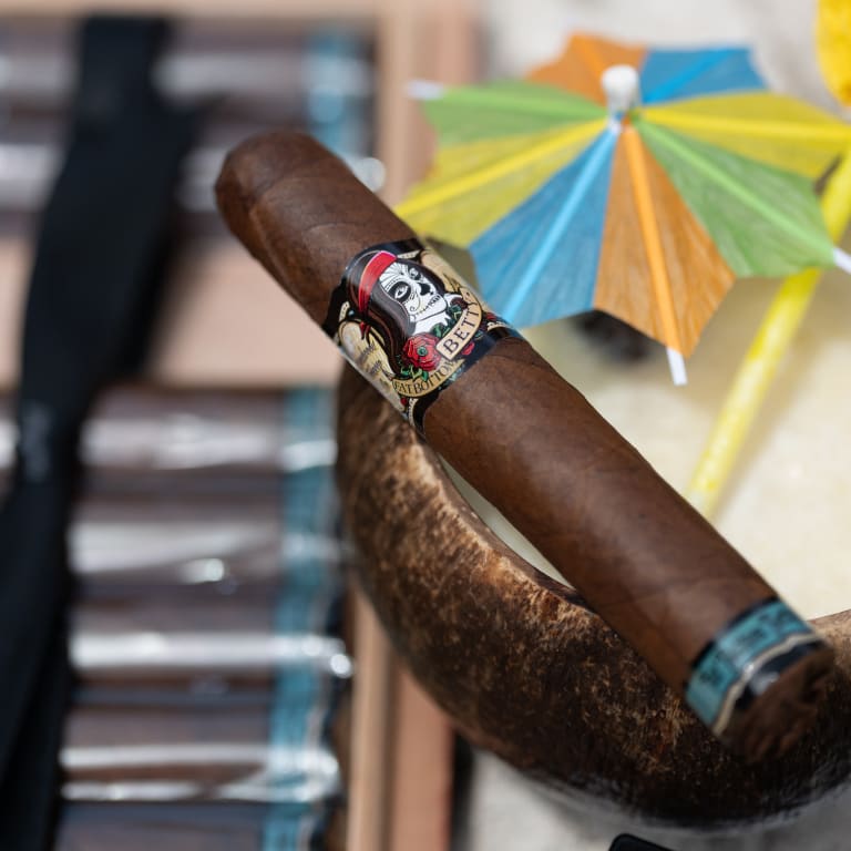 Cigar with a decorative band in front of colorful umbrellas