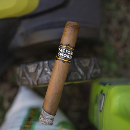 Cigar with 'Factory Smoke' label against a blurred background