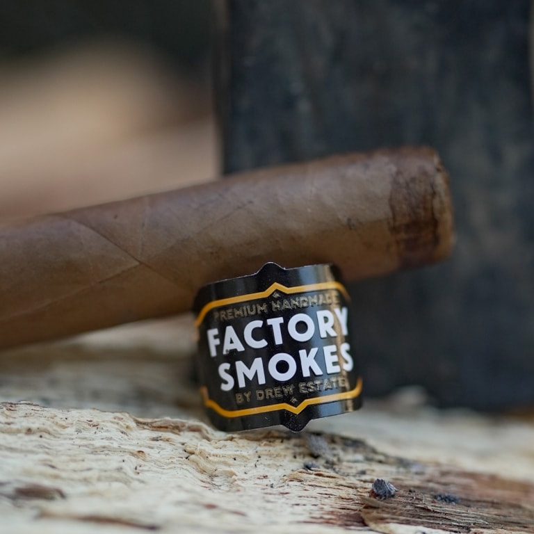 Cigar with Factory Smokes label on a wooden surface