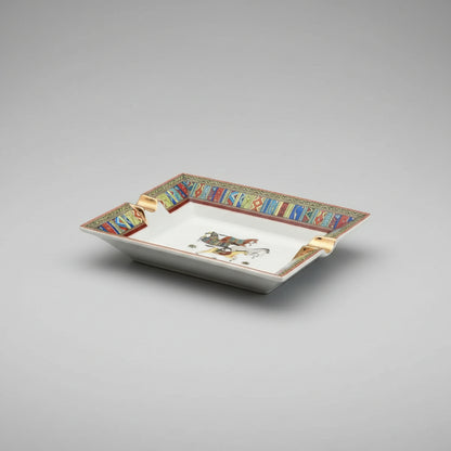 A rectangular ceramic ashtray with a white center and a highly decorative, colorful geometric border. The center features a painted illustration of two horse riders.
