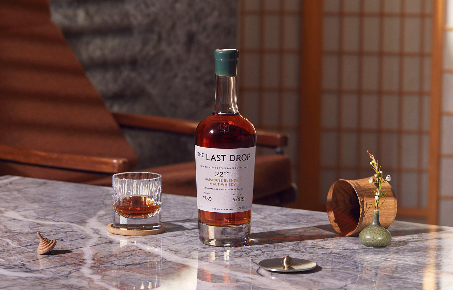 Bottle of 'The Last Drop' whisky with a glass on a marble surface.