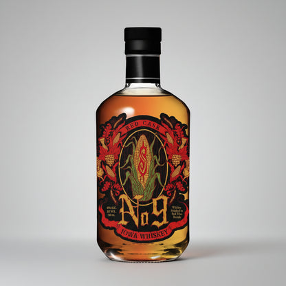 A bottle of Iowa Whiskey No. 9 Red Case whiskey with a black cap and a detailed label featuring red, gold, and green corn illustrations.